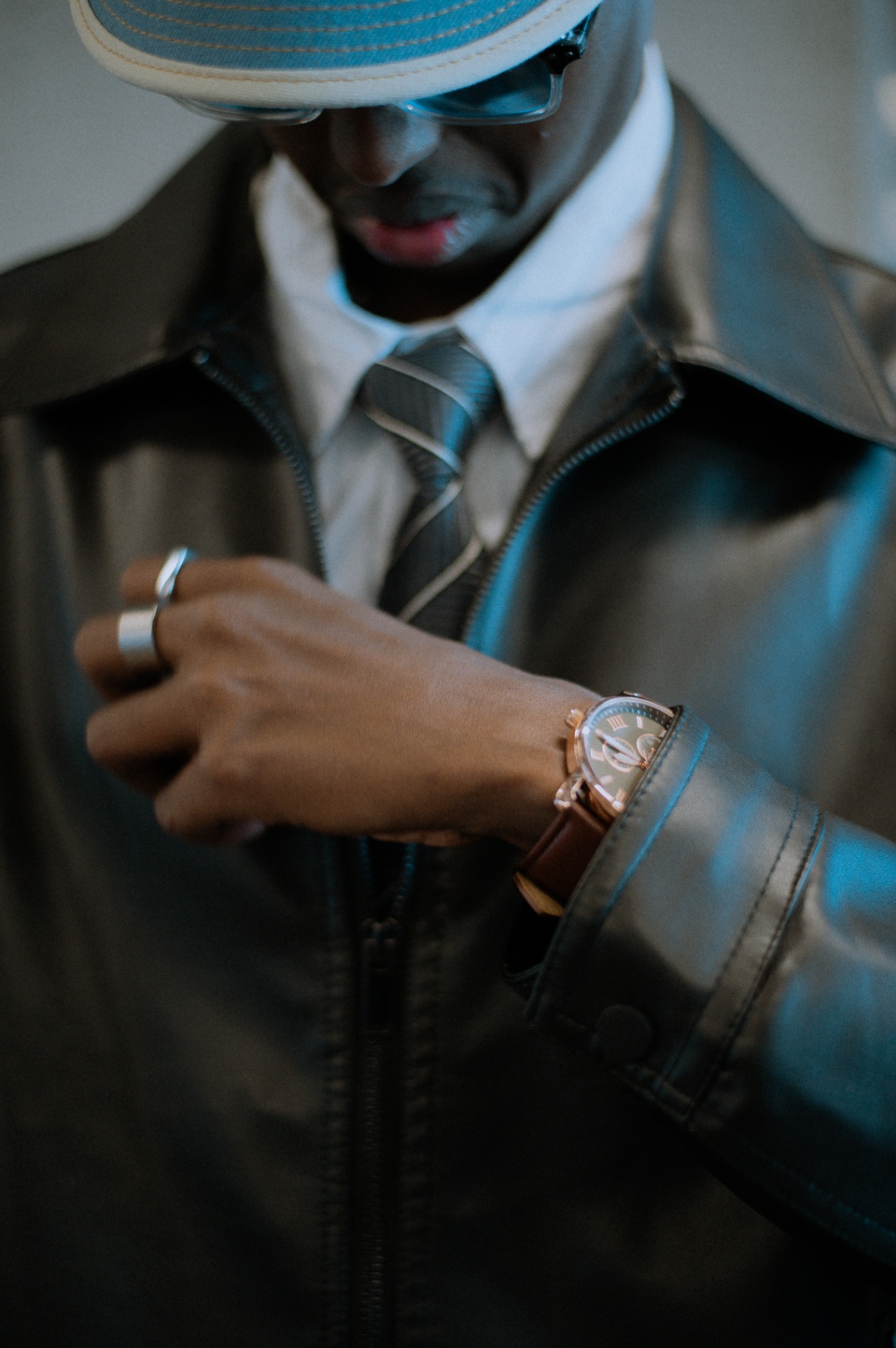 Close-up of watch, rings, and tie under a leather jacket