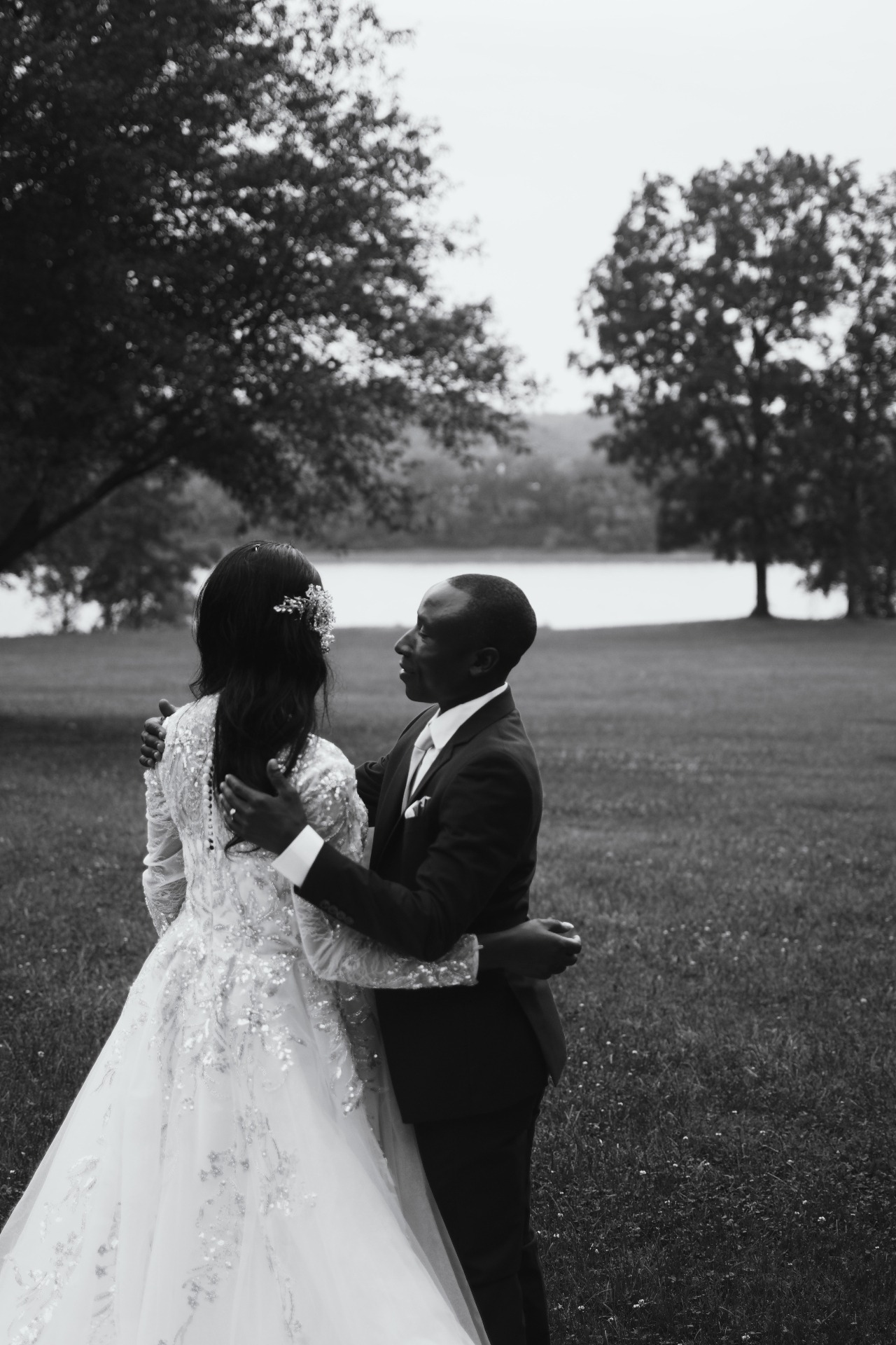 Bride and groom embracing by the lake in black and white