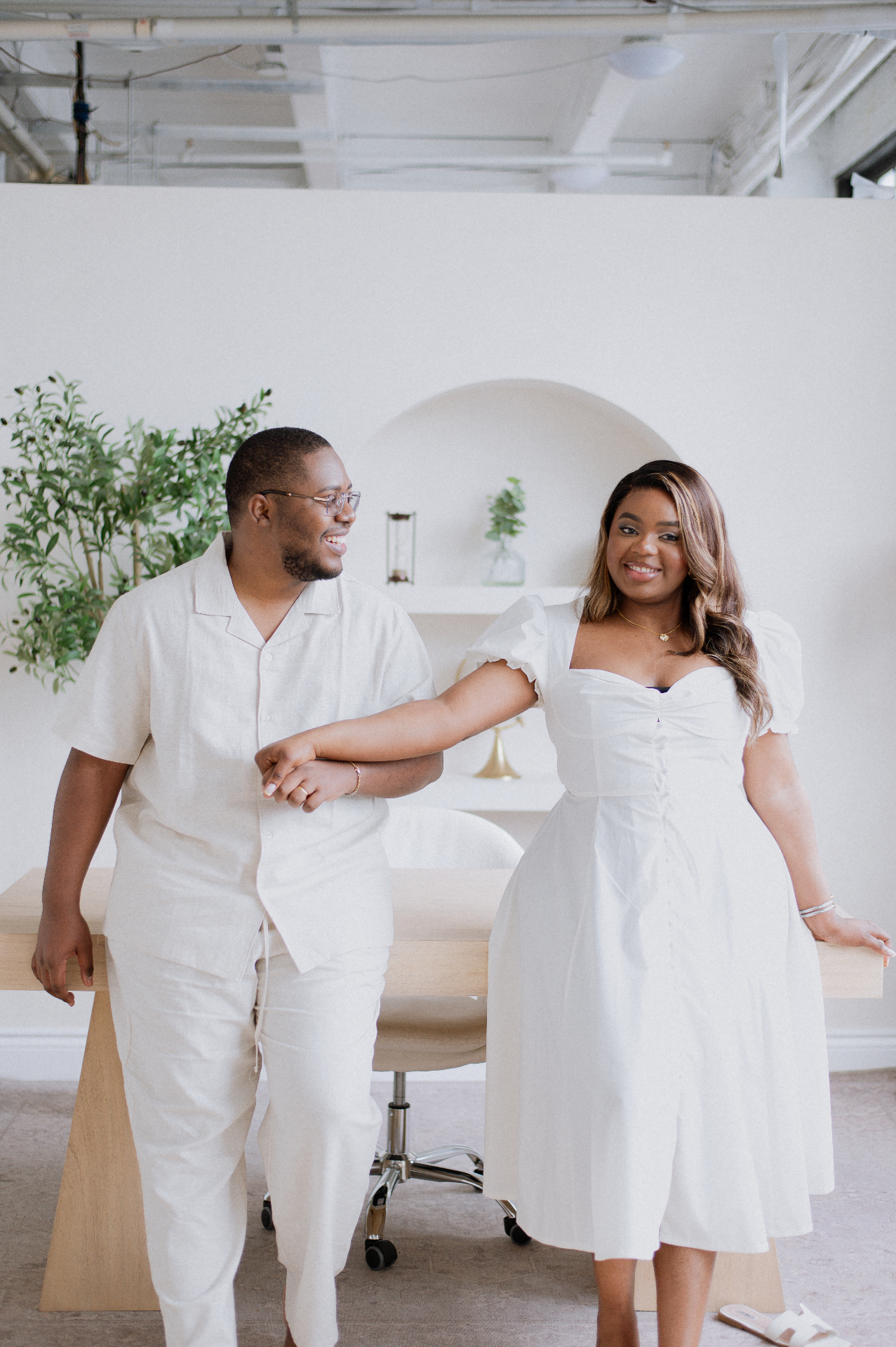 Couple in linen whites laughing in a bright studio