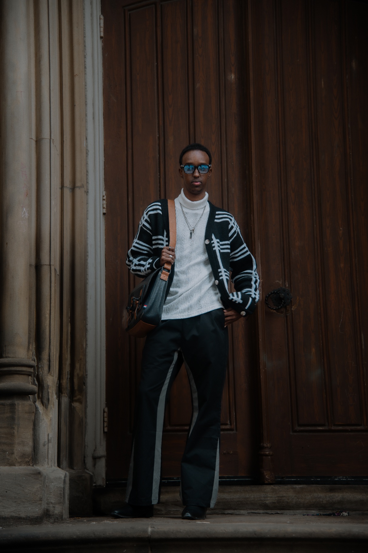 Editorial street portrait in a checked cardigan by a wooden doorway