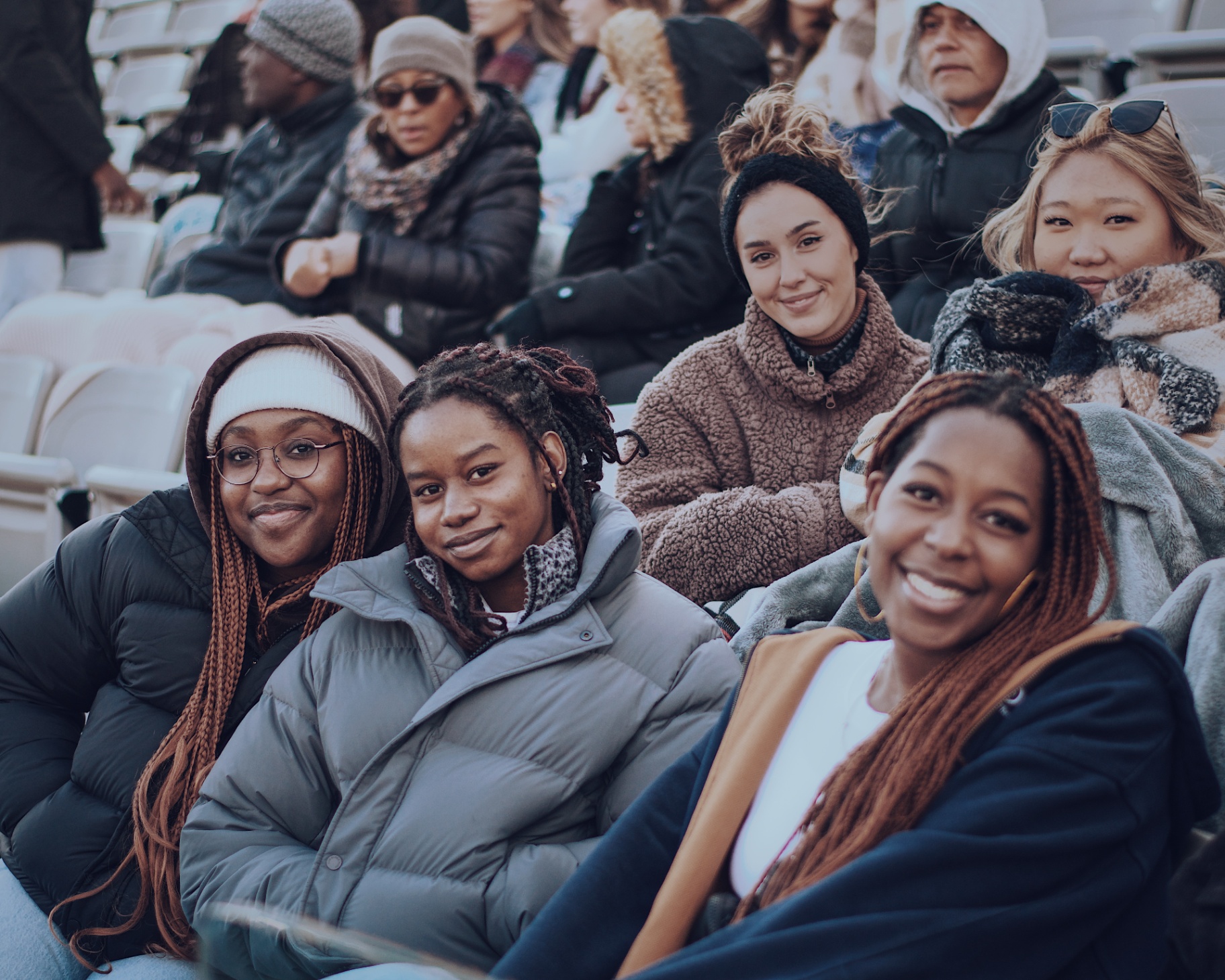 Friends smiling together in the stadium seats