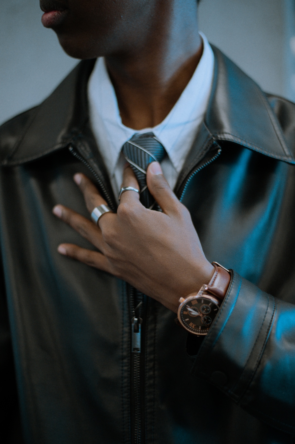 Detail of hands adjusting a tie with a leather-strap watch