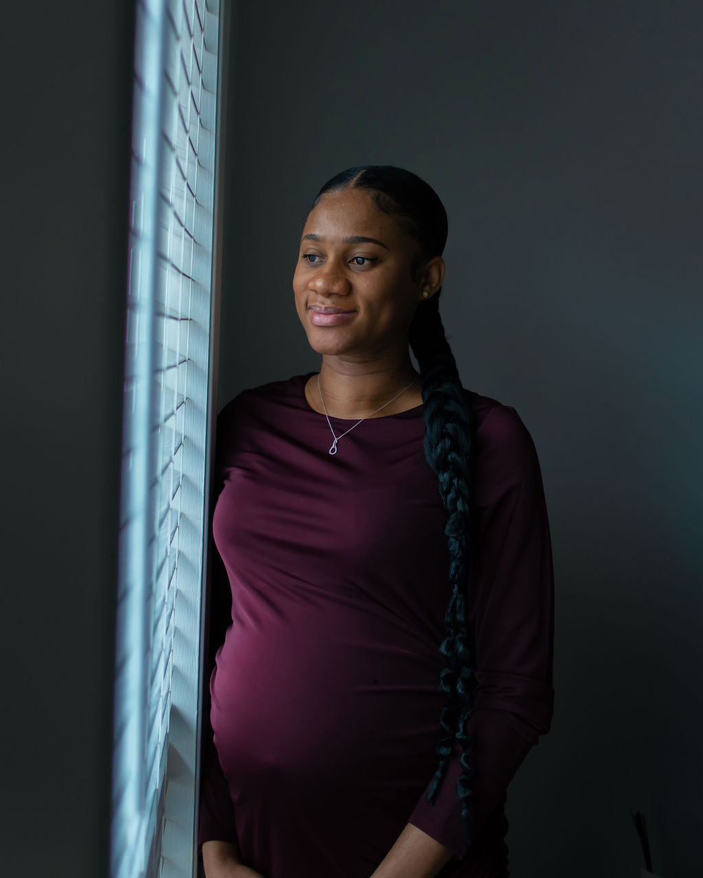 Maternity portrait in plum, by the window
