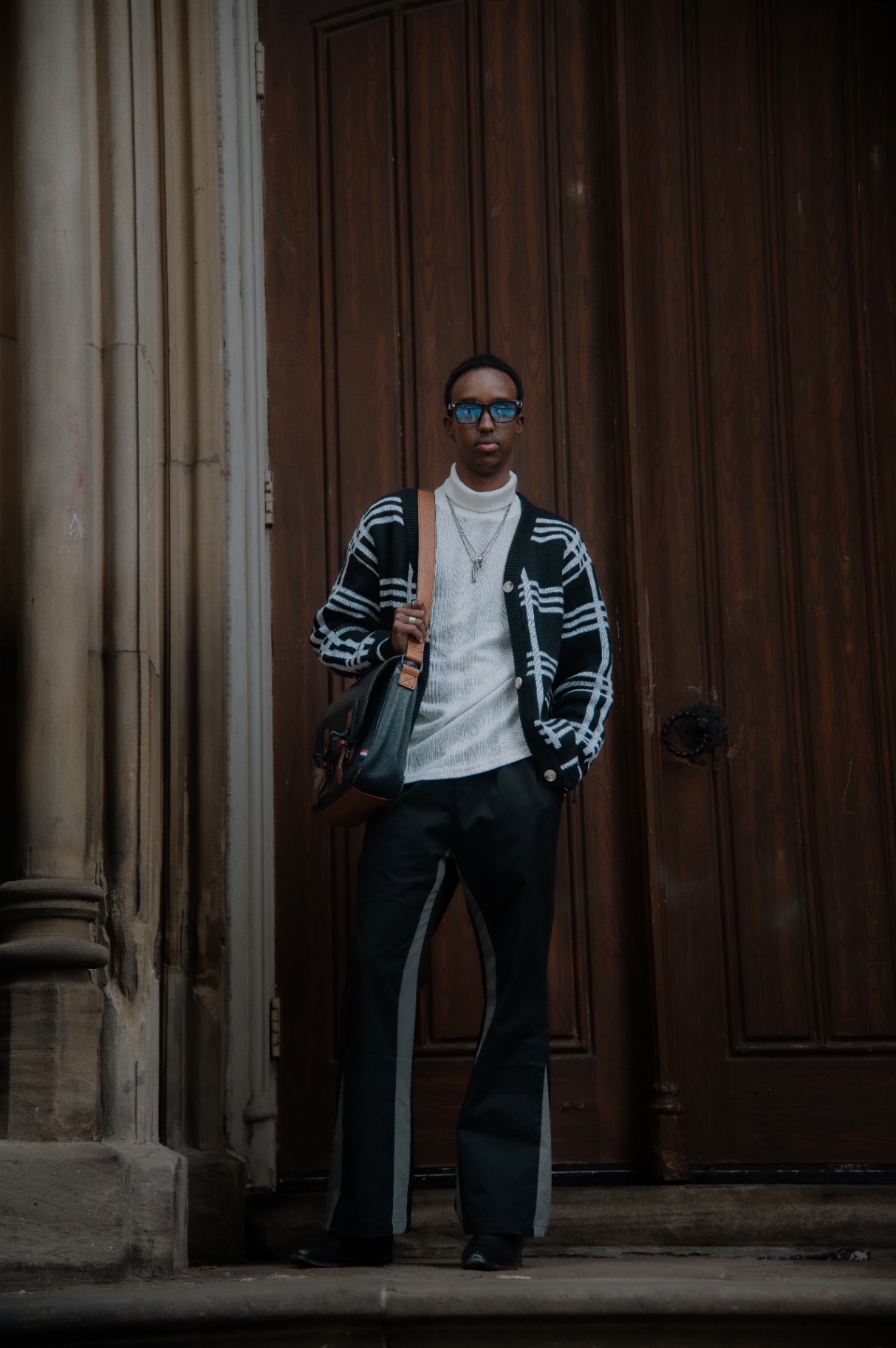 Full-length street portrait framed by a grand wooden doorway